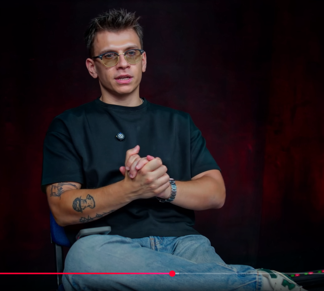Is the person he is looking at a man or a woman, and what message is he sending to that person with his facial expression?